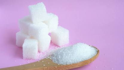 uses for sugar: White sugar cube on pastel pink background.