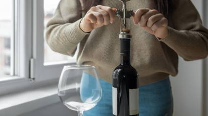 how to store wine after opening: Woman opening wine bottle with bottle opener