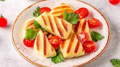 Grilled halloumi cheese served with tomatoes and parsley as part of a guide answering the question "What does Halloumi cheese taste like?"