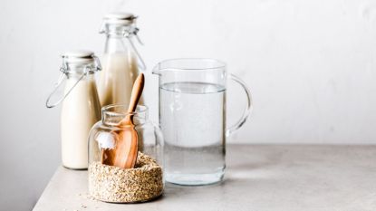 A pitcher of water beside of a jar of oats and oatmilk, which are used to make the viral Oatzempic diet