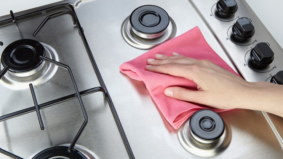 woman cleaning set-top stove with rag