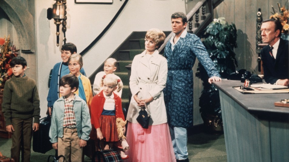 Robert Reed and Florence Henderson stand in a hotel lobby with their television family in a still from the TV series 'The Brady Bunch,' circa 1969. (L-R) Christopher Knight, Barry Williams, Mike Lookinland, Maureen McCormick, Eve Plumb, Susan Olsen, Henderson, Reed, unidentified.