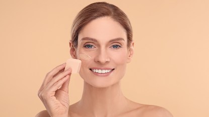 Woman smiling and using a makeup sponge to apply foundation after learning how to clean makeup sponges