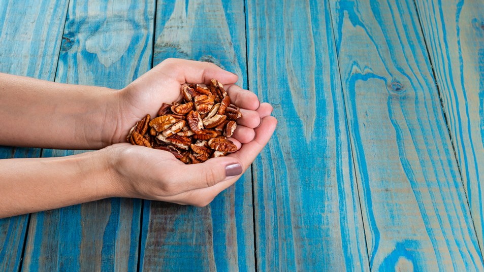 A woman's hand holding a handful of pecans, which studies show can help reduce your risk of diabetes