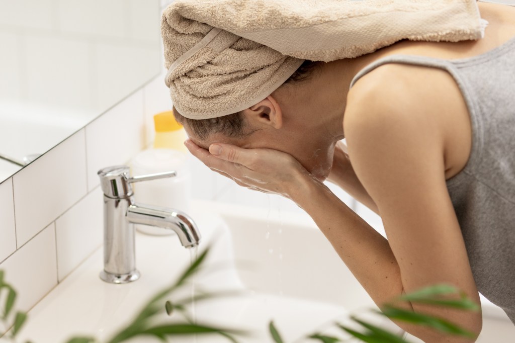 woman washing face in sink for nighttime skincare routine