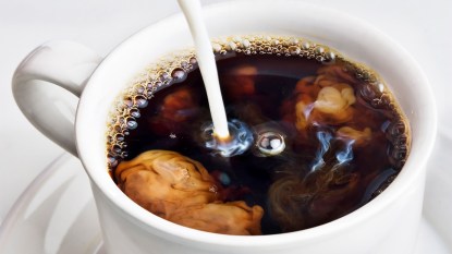 Curdled milk being poured into a cup of coffee.