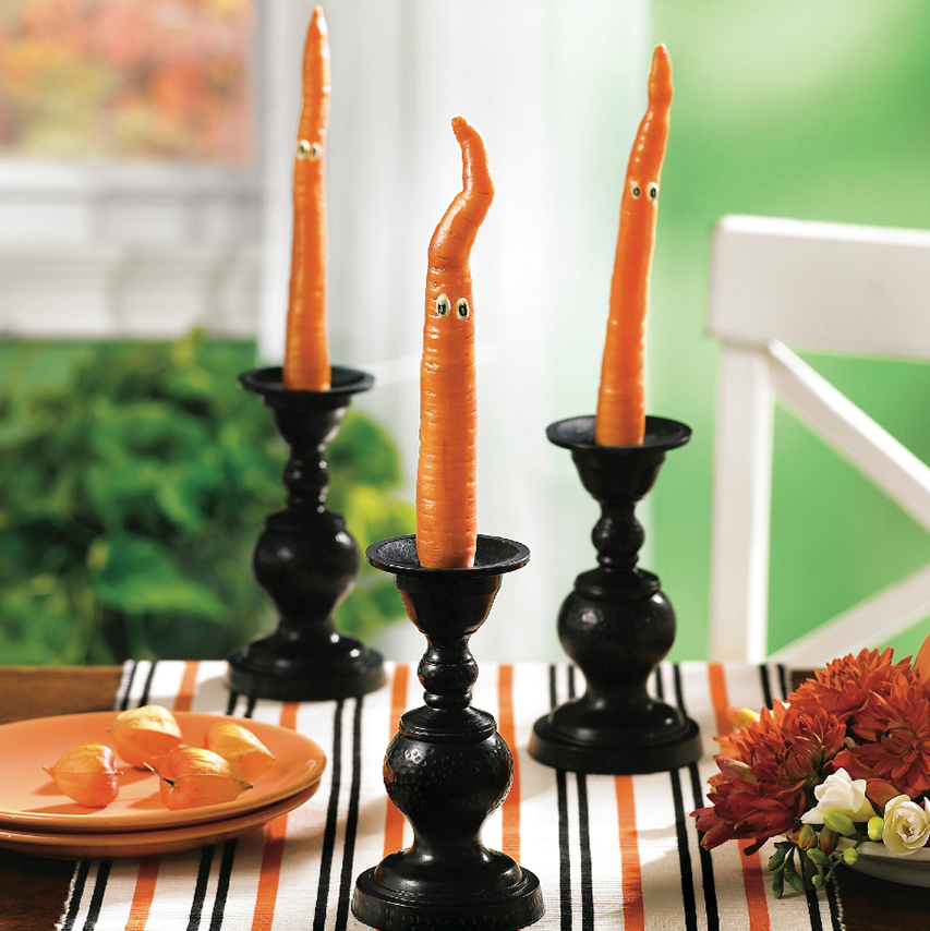 Halloween Centerpiece Ideas: Spooky-cute carrot creature displays that show a carrot placed in a candleholder with little eyes