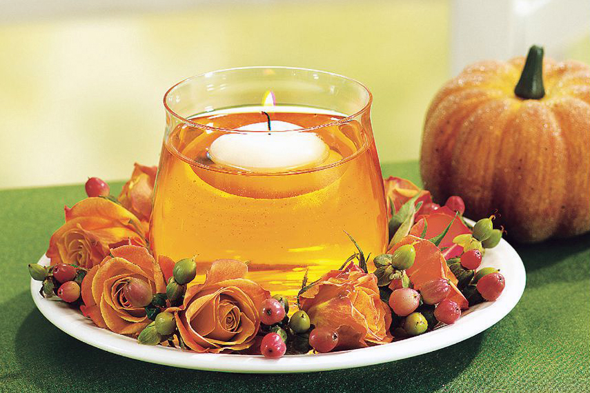 Floating candle display in glass cup placed onto a plate kissed with fall blooms
