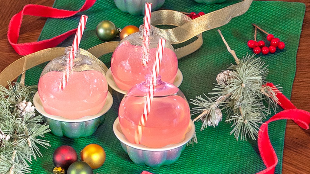glass ornaments with top removed, filled with cocktails and resting in a mini muffin tin