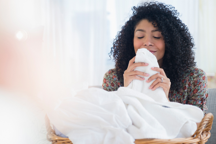 Junge Frau riecht an ihren frisch gereinigten weißen Handtüchern.