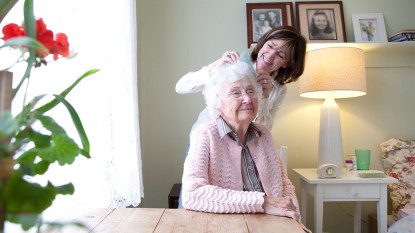 Woman brushing elderly woman's hair; caregiver burnout