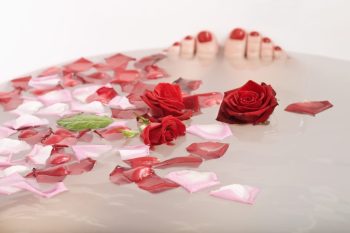 feet in a bath with rose petals on bathwater for Valentine's Day