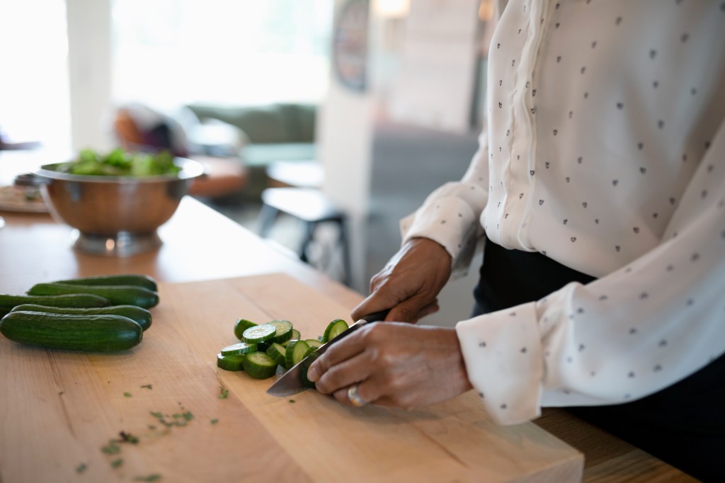 Uses for white vinegar: A woman chops green veggies on her clean cutting board