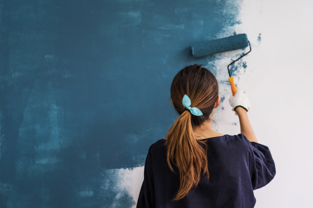 Uses for white vinegar: A woman paints her house blue while not worrying about the smell