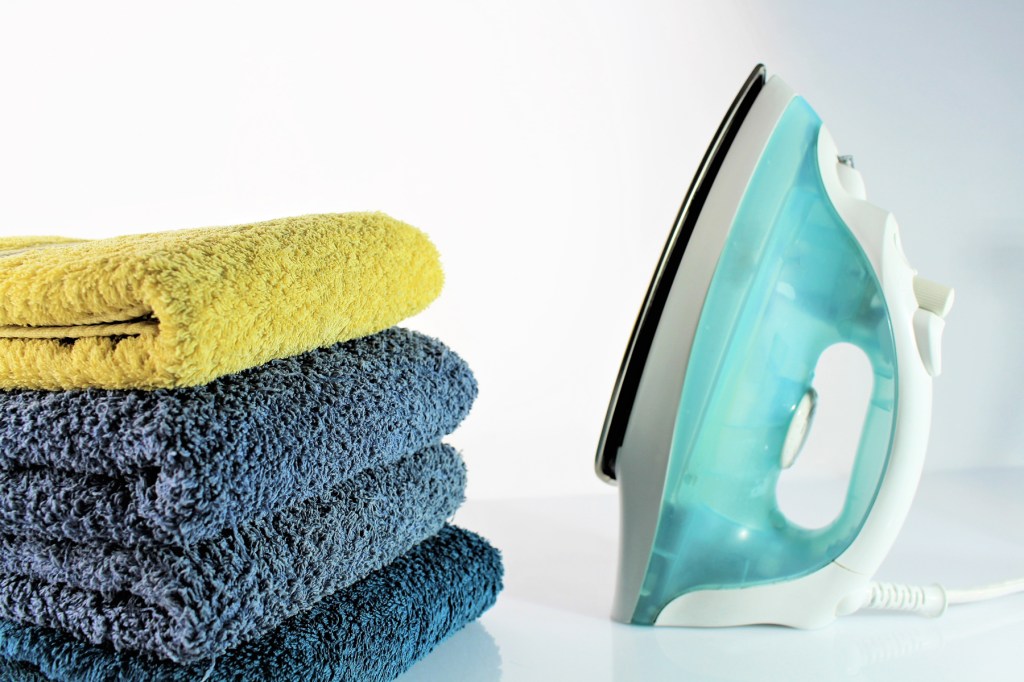 Uses for white vinegar: A now clean iron sits next to three towels