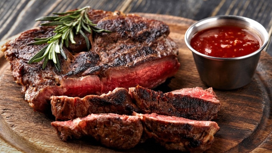 medium rare steak on wooden board with sauce