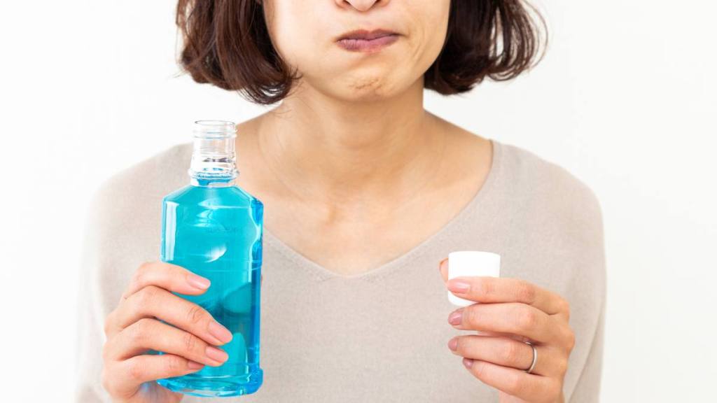 Woman using mouthwash ; How to get rid of garlic breath
