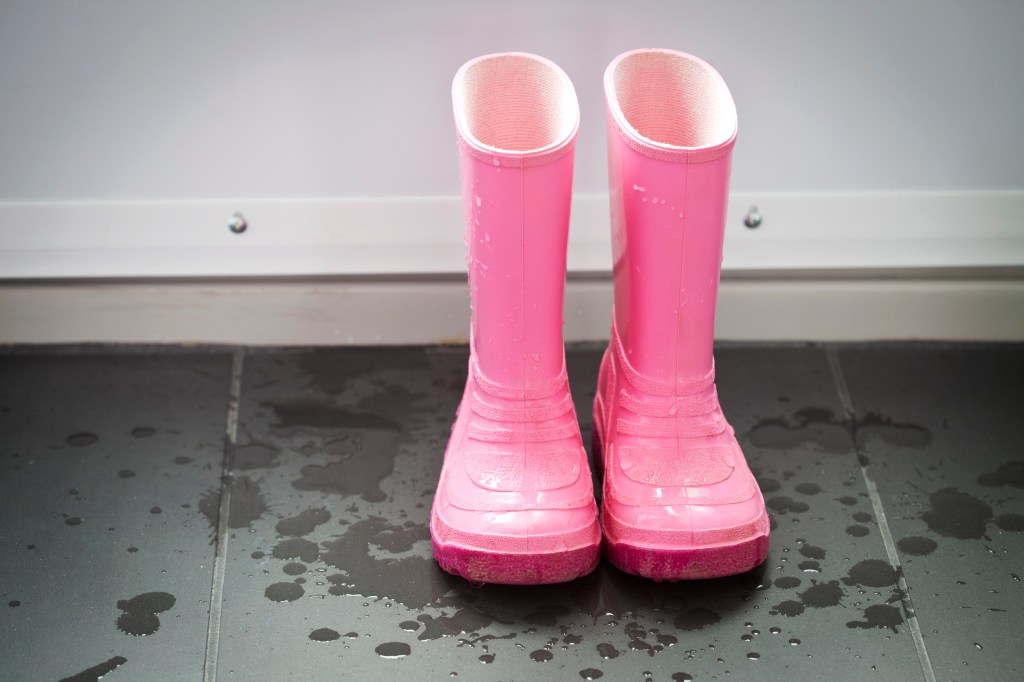 A pair of wet pink galoshes in the entrance way.