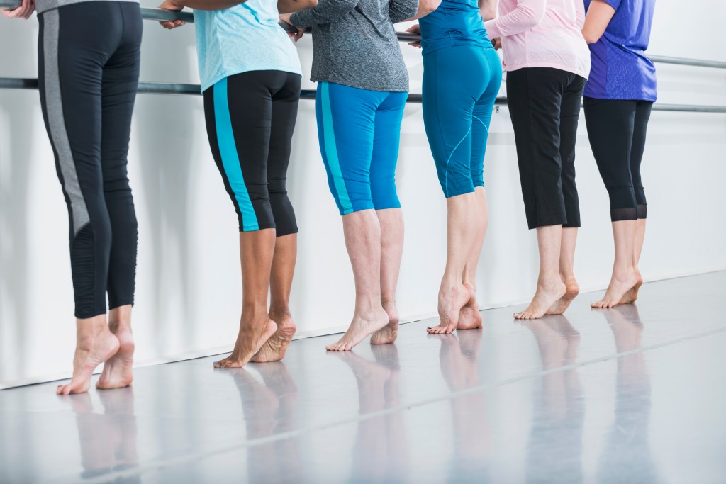 Women working out with ballet barre.
