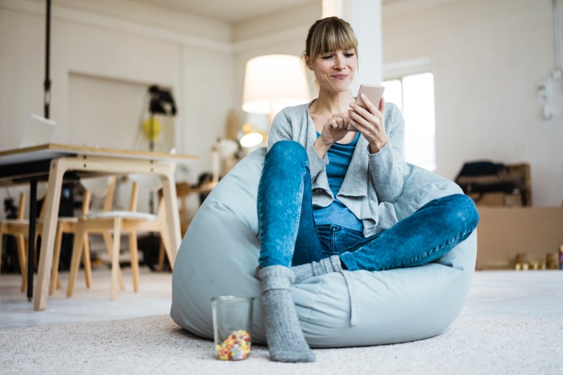 Smiling woman sitting in beanbag using cell phone
