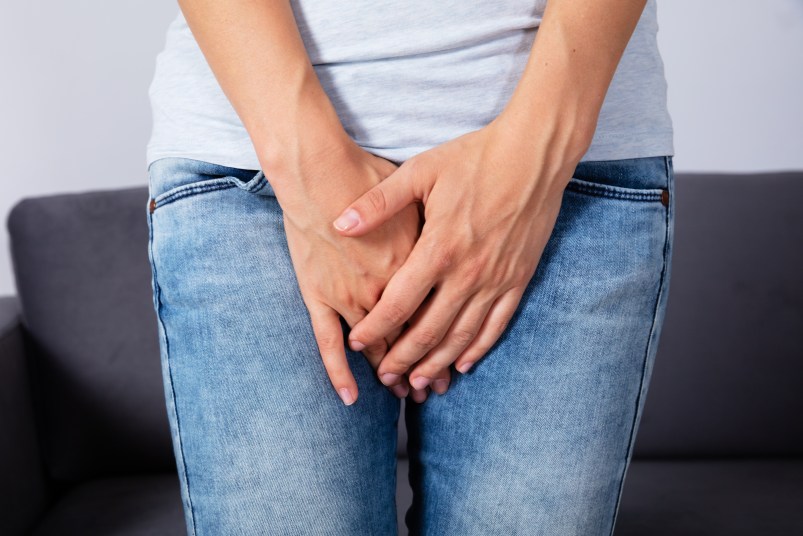 woman struggling with urinary incontinence holding her crotch
