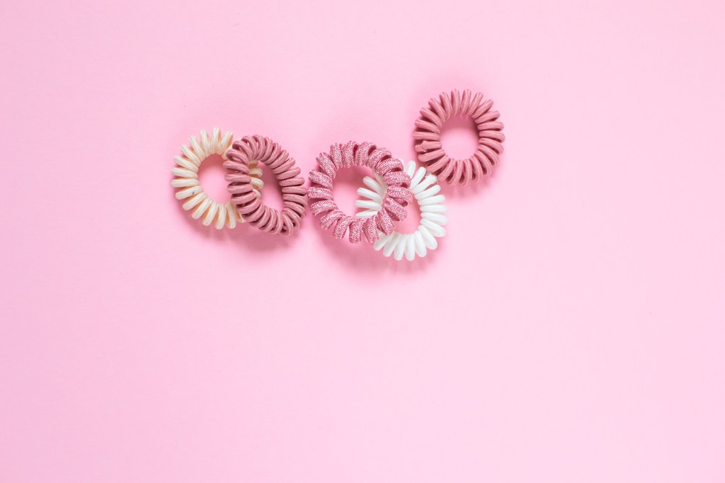 Hair spiral scrunchies on pink background, beauty concept, flat lay