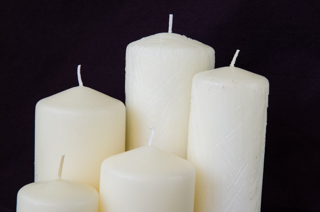 group of unlit white candles against black background
