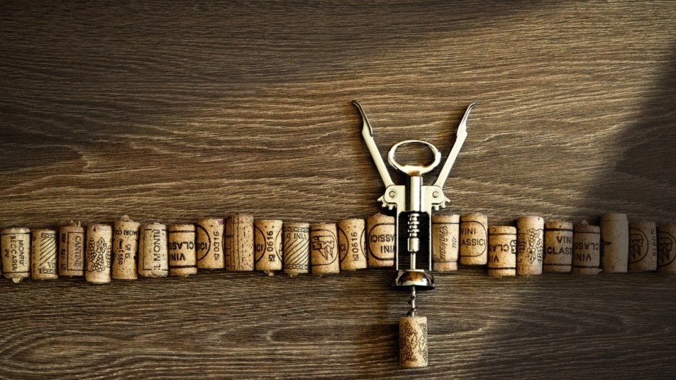 wine corks in a row on a table with one bottle opener