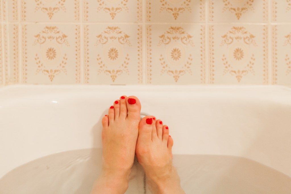Young female feet in bathtub