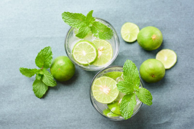 High Angle View Of Drinks With Limes And Mint Leaves On Table