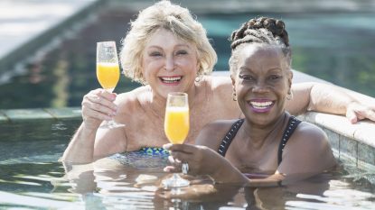 Two mature women enjoying cocktail in swimming pool