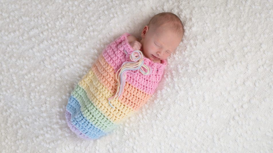 Newborn Baby Girl in a Rainbow Colored Pouch