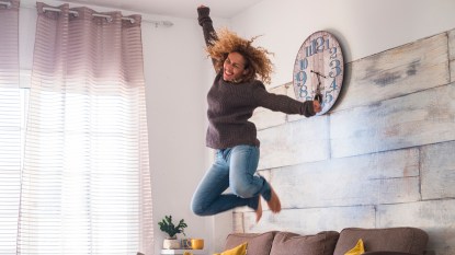 Woman jumping on living room couch