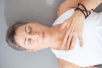 mature woman lying down on her back with eyes closed and hand on chest