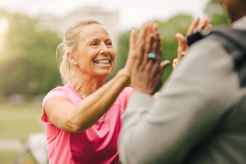 Happy senior woman giving high-five to female friend in park