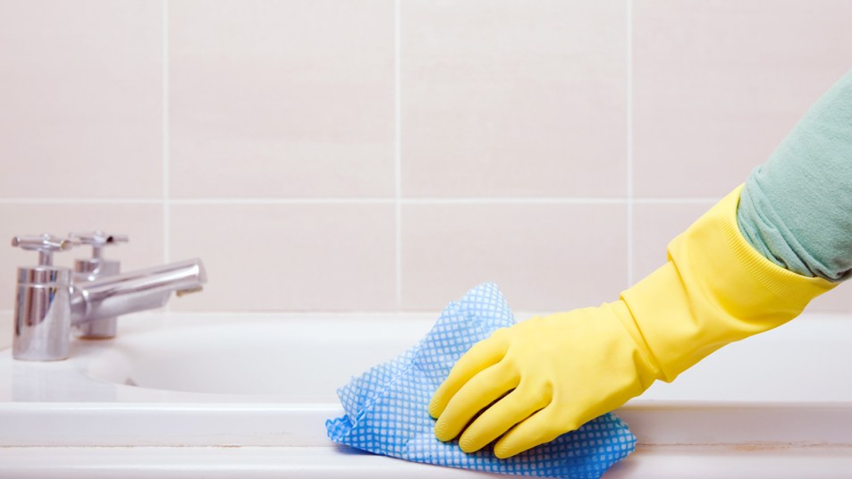 Gloved hand scrubbing bath tub