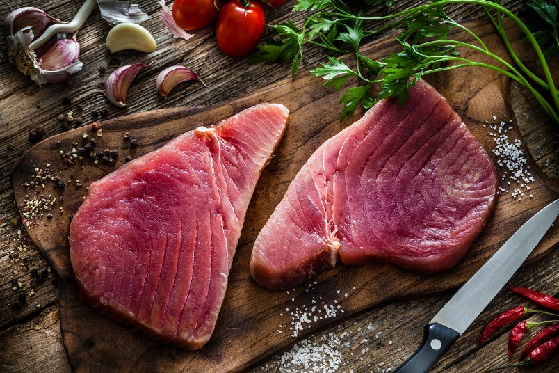 Two raw tuna steaks on rustic wooden table