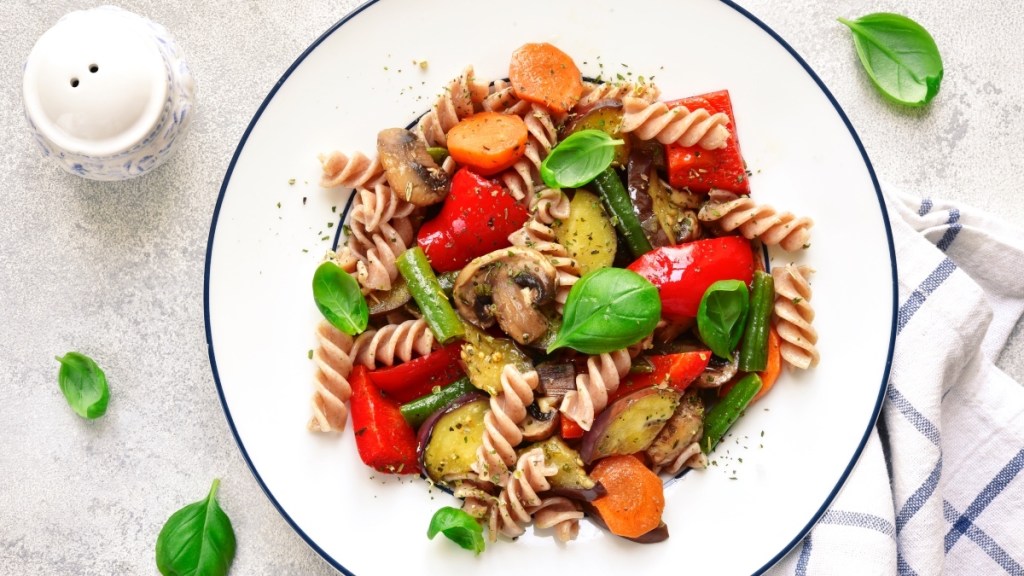 A plate of whole wheat pasta, tomatoes, basil and veggies, all of which help balance hormones