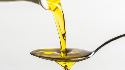 Oil being poured into a spoon_hydrogenated oil featured image