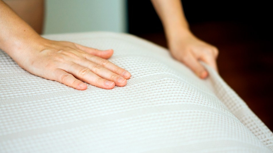 Hands smoothing out bed sheets