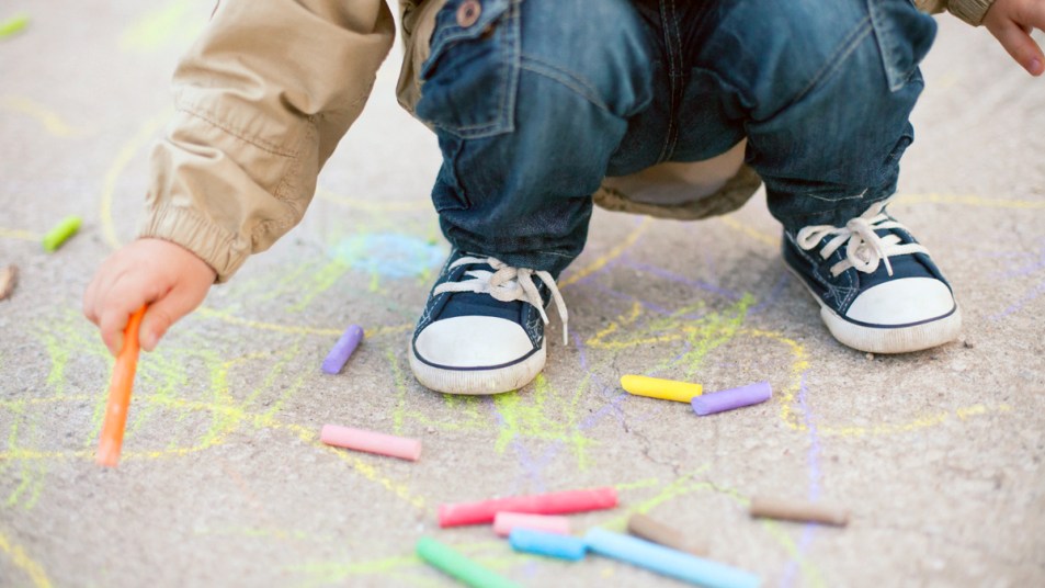 Little boy drawing on sidewalk with chalk