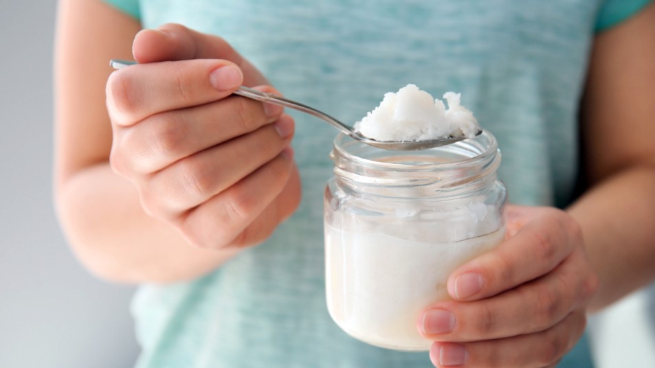 Woman scooping coconut oil out of jar