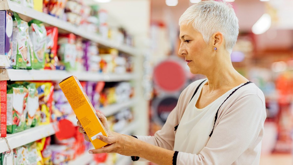 Woman in grocery store reading label for hydrogenated oil