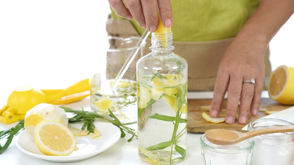 woman making her own DIY cleaning product recipes with lemon, vinegar and more