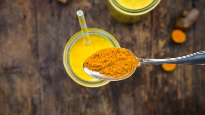 A spoonful of turmeric over a smoothie glass because it's going to be added to help lose weight