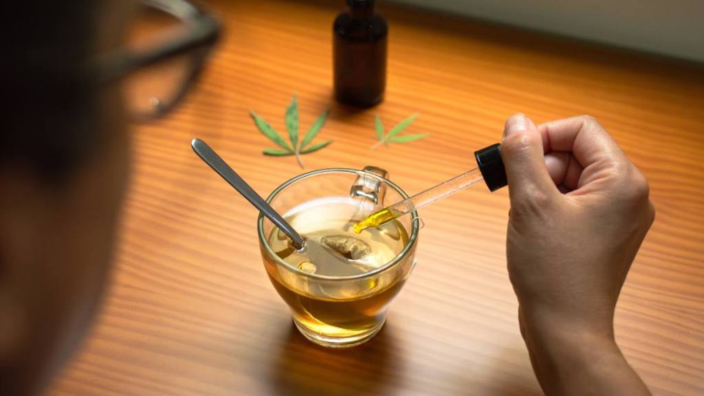 woman putting cbd oil in a drink