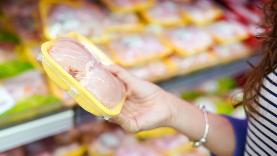 Woman holding chicken at grocery store
