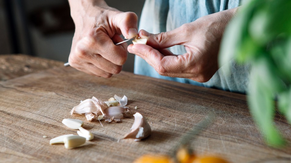 Woman peeling garlic with knife