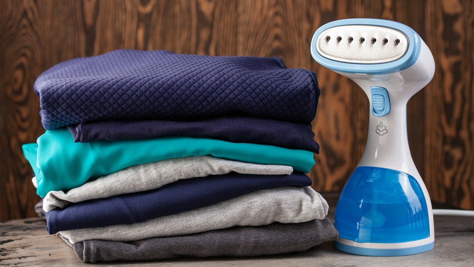 handheld steamer next to a stack of clothes