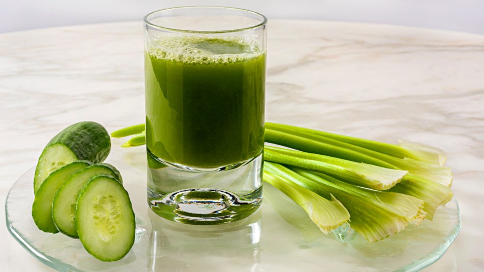 Celery and cucumbers around glass of green juice